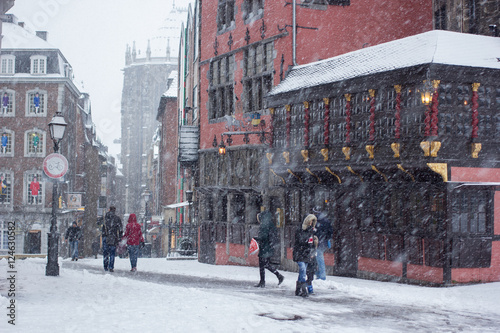 Wintereinbruch mit Neuschnee Flocken schneien mit Wind auf die Leute in Einkaufsstraße
