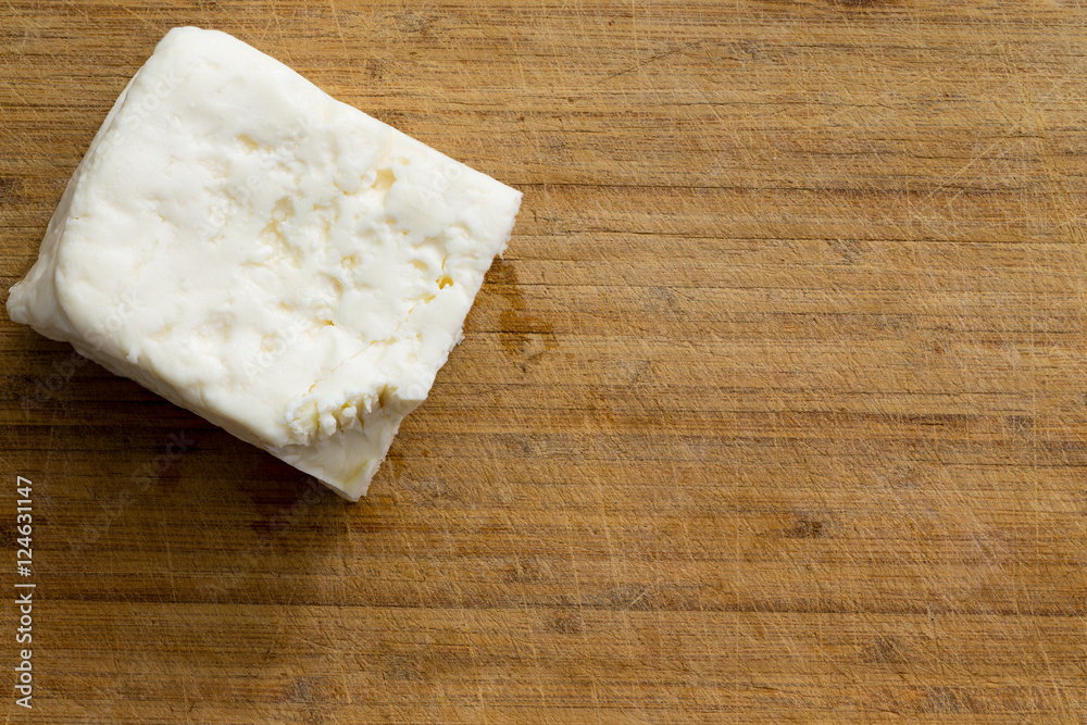 Cube of white cheese on cutting board