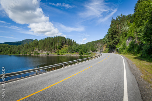 Empty curved road on the lake's shore in Norway