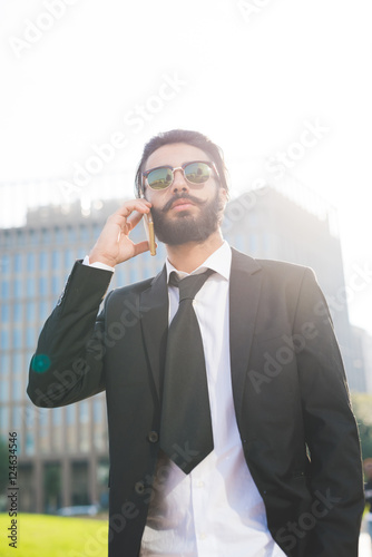 Half length of young handsome black hair caucasian modern businessman walking in the city talking smart phone - business, working concept