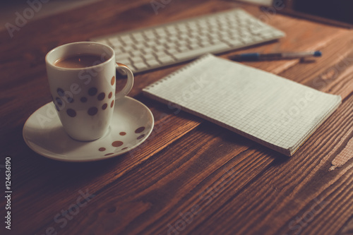 Coffee, notebook and keyboard on a dark wooden table