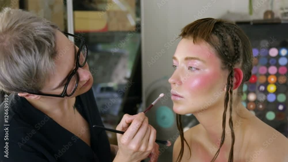 Stylist to apply makeup on the model's face Stylist to apply makeup on the model's face