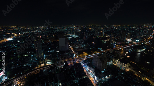 Night life in Bangkok, Thailand. Panoramic view of illuminated metropolis with car traffic on highways and boat traffic on the channel