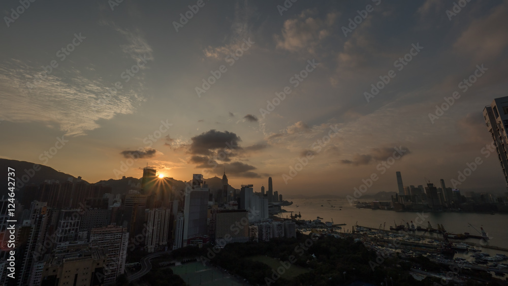Cityscape of Hong Kong at sunset. View to the city with modern high-rise architecture and harbour with dockyard