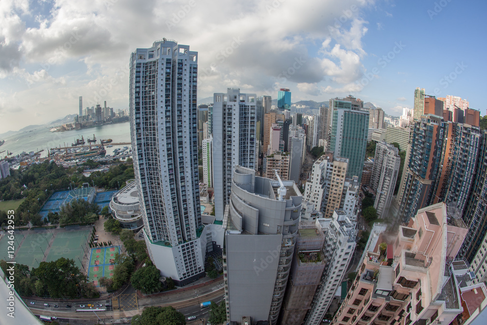 Obraz premium Wide angle shot of Hong Kong in daytime. Clouds sailing over the city with high-rise architecture, harbour with dockyard in background
