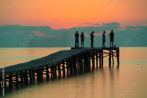 people greeted the sunrise on a wooden quay