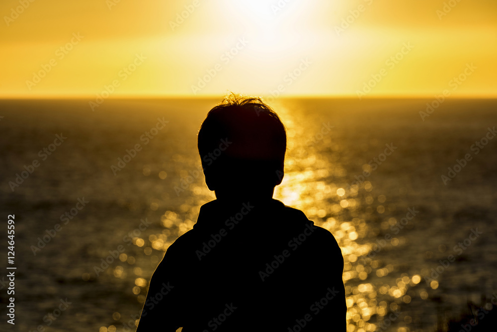 Fototapeta premium Silhouette of a teenager boy on sunset