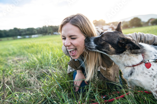Beautiful young woman with dog in green sunny nature