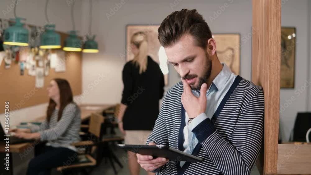 young handsome bearded man uses touchscreen tablet in the modern startup office. young handsome bearded man uses touchscreen tablet in the modern startup office.