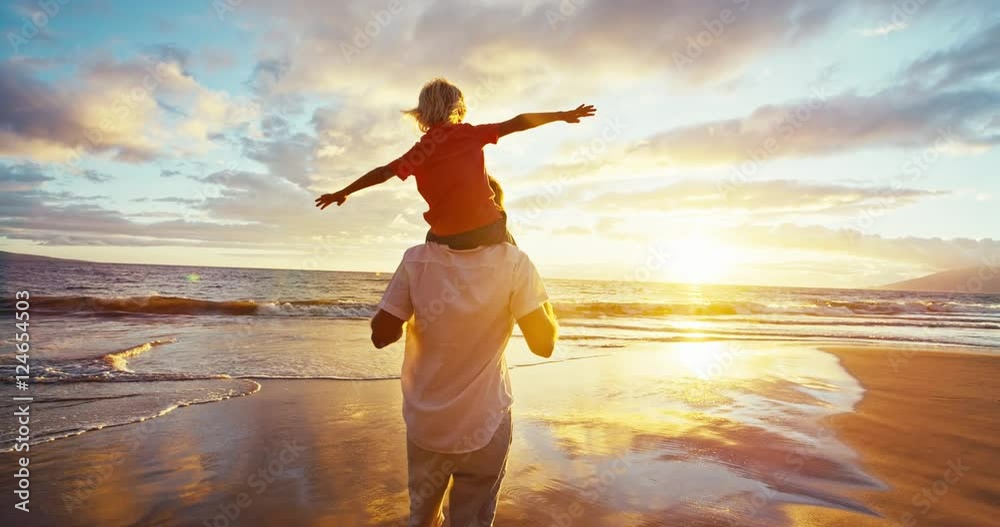 Happy father and son playing on the beach at sunset