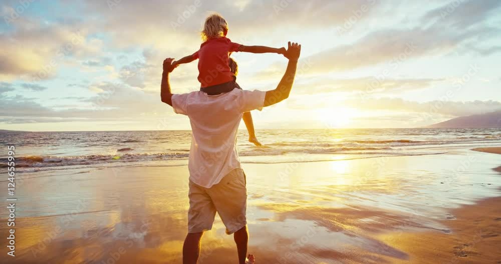 Happy father and son playing on the beach at sunset
