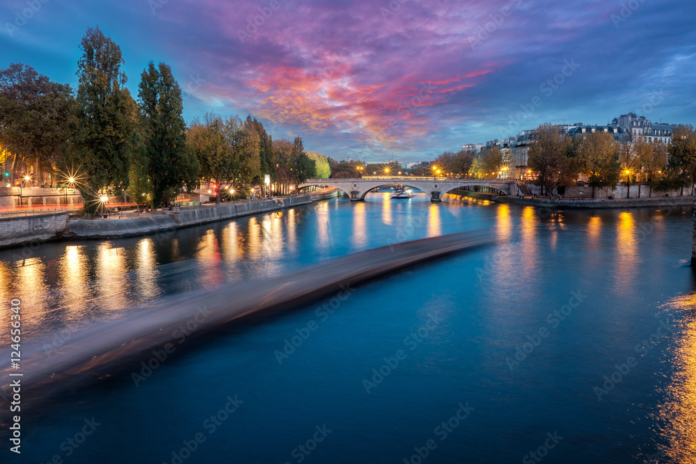 River Seine in Paris, France at dusk, in autumn. Long exposure of passing boat.