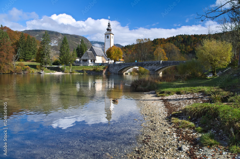 Autumn view of the stone bridge and the Church of St. John the Baptist at Lake Bohinj (Bohinjsko jezero), Slovenia
