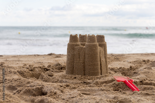 Kinder bauten eine schöne Sandburg am Strand, mit Meer im Hintergrund