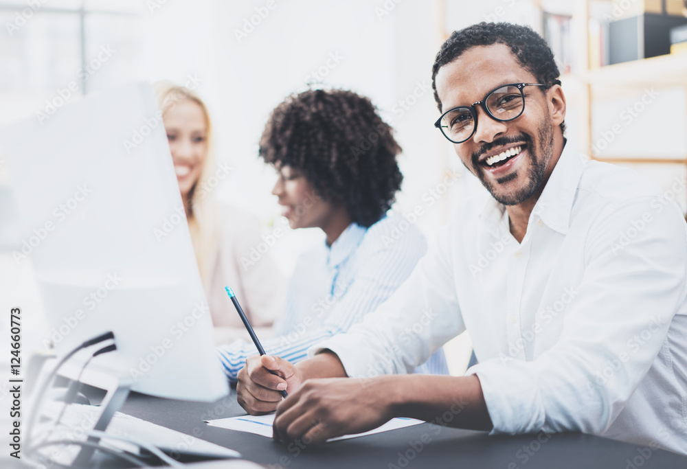 Dark skinned entrepreneur wearing glasses, working in modern office.African american man in white shirt smiling at the camera.Horizontal,blurred background Dark skinned entrepreneur wearing glasses, working in modern office.African american man in white shirt smiling at the camera.Horizontal,blurred background