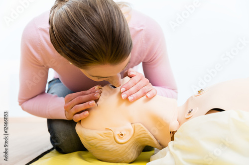 Frau übt Mund-zu-Mund-Beatmung an Rettungs-Dummy photo