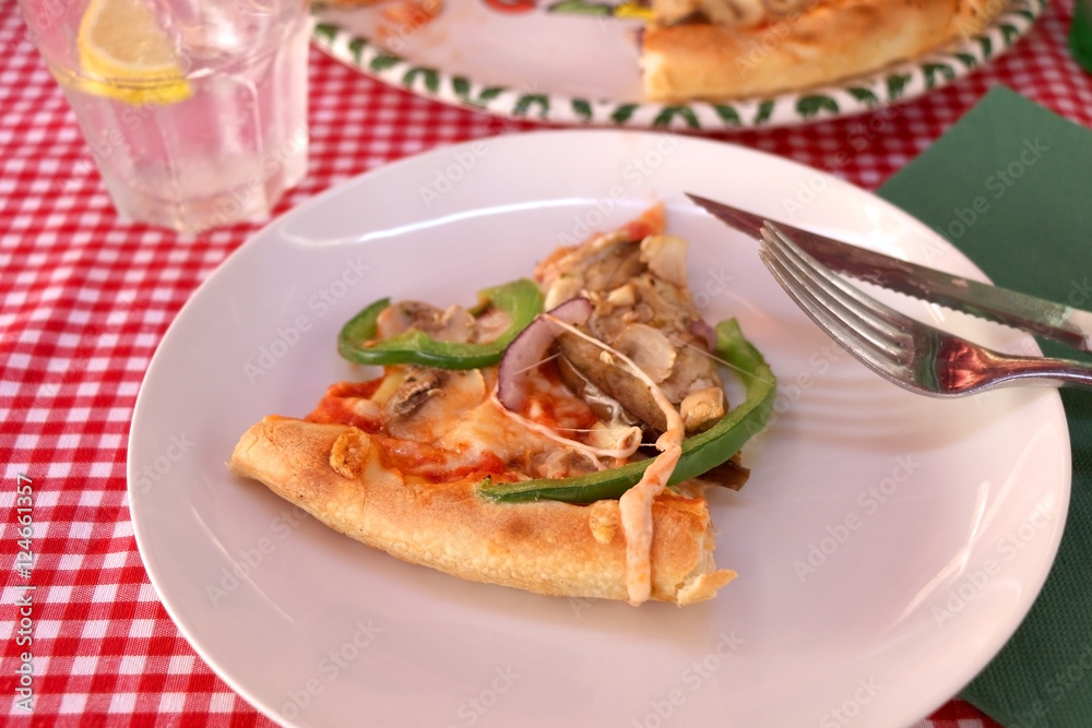 Slice of vegetarian pizza with cheese, tomato sauce, green peppers, mushrooms and onion in a pizzeria. Selective focus. Slice of vegetarian pizza with cheese, tomato sauce, green peppers, mushrooms and onion in a pizzeria. Selective focus.