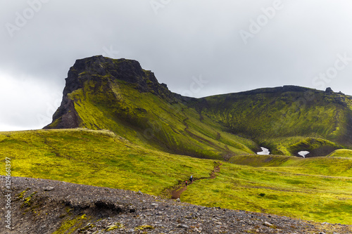 Big tall hill with are climbing up tourists in Iceland