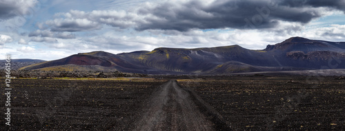 Panoramic view Road on black sand in Iceland on mount background. Dramatic black landscape in Iceland
