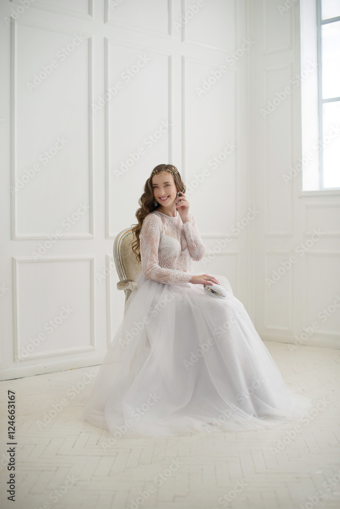 Beautiful young bride sitting on a chair in white room. Beautiful young bride sitting on a chair in white room.