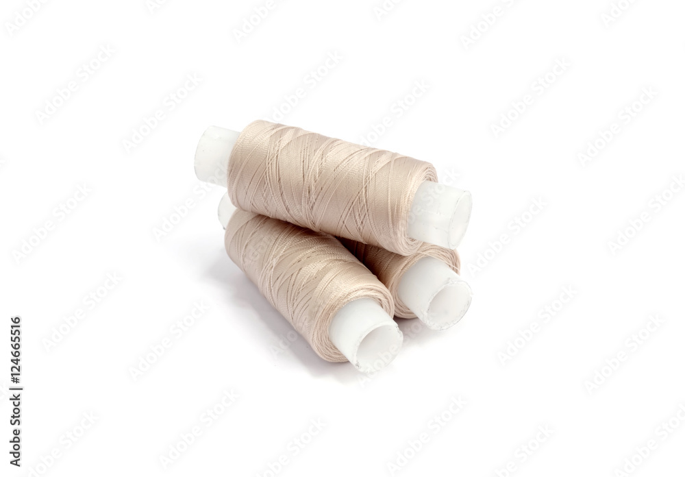 Spools of beige cotton threads on white background Spools of beige cotton threads on white background