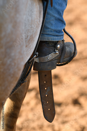 Horseman leg in boot at stirrup on horse during the riding