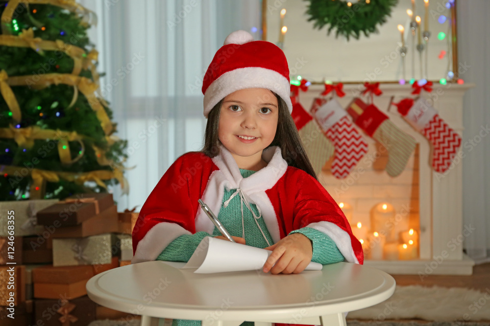 Cute little girl writing letter to Santa Claus at table Cute little girl writing letter to Santa Claus at table