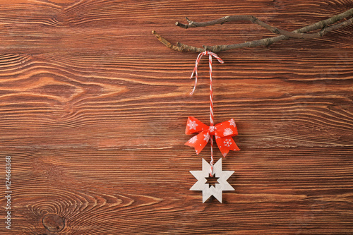 Christmas decor hanging on branch against wooden background