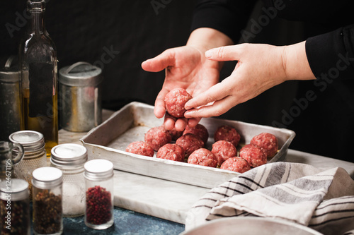 Beef swedish meatballs bowl. Female hand preparing beef meatballs in cooking sheet on marble board. rustic style.