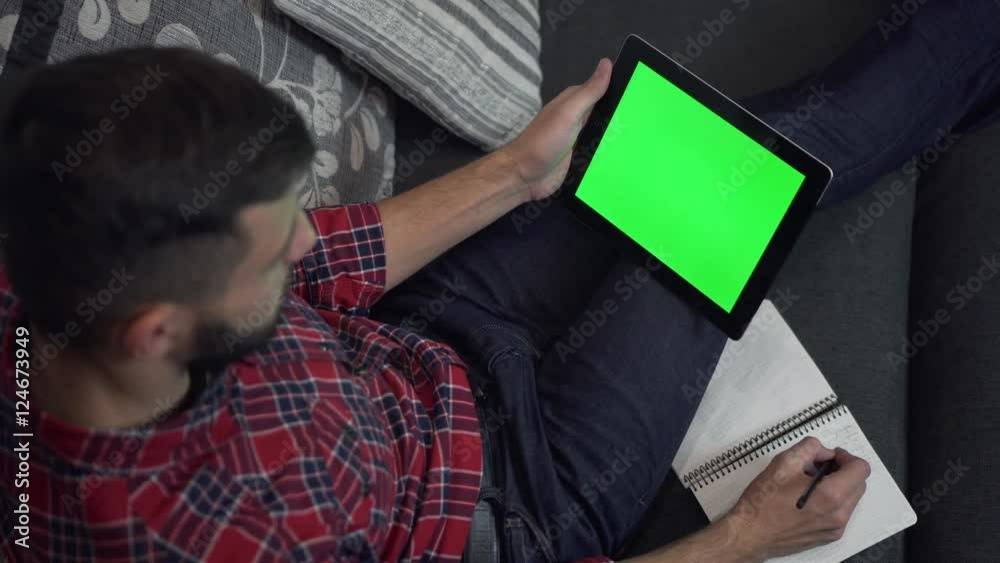 Man Use Tablet PC with Green Screen and Notebook Man Use Tablet PC with Green Screen and Notebook