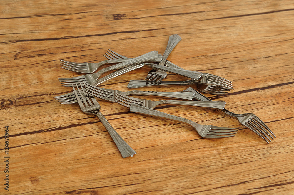 A pile of cake forks isolated on a wooden background A pile of cake forks isolated on a wooden background