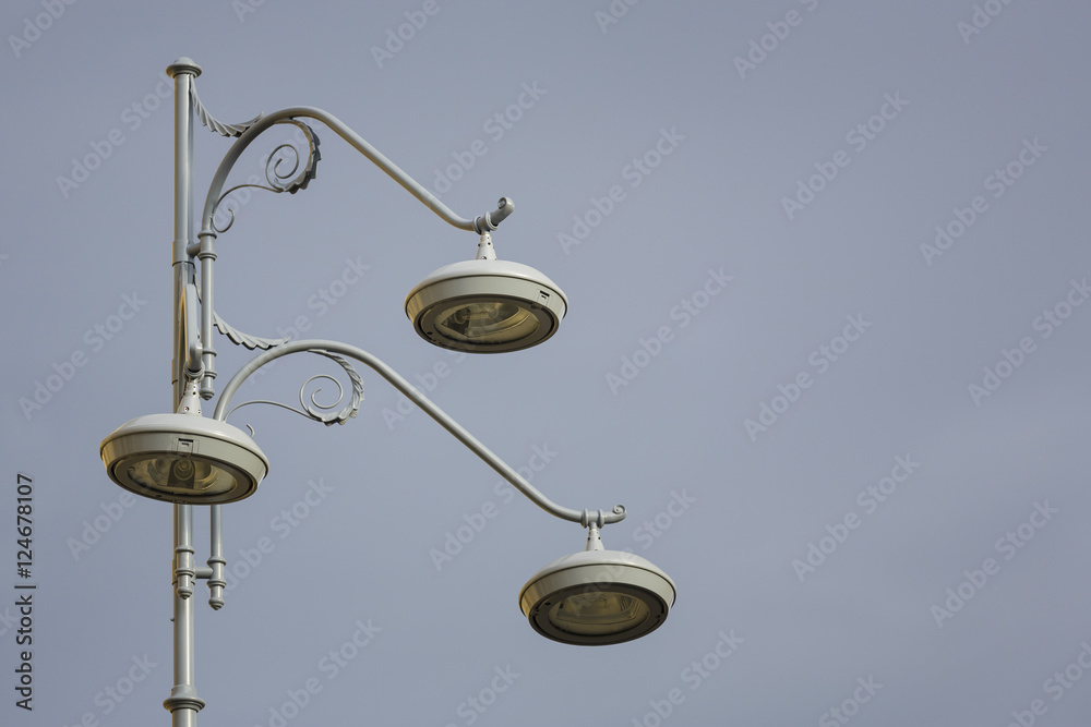 Closeup of retro stylish street lamppost with three bulbs over grey cloudy sky. Copy space. Closeup of retro stylish street lamppost with three bulbs over grey cloudy sky. Copy space.