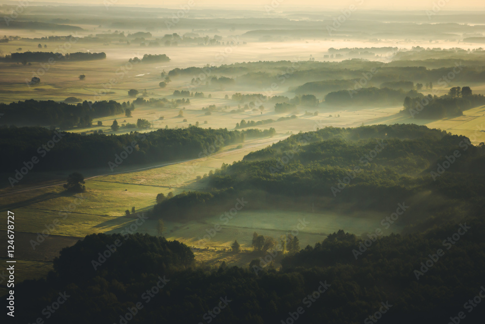 Fototapeta premium Sunrise fog over fields and forest landscape.