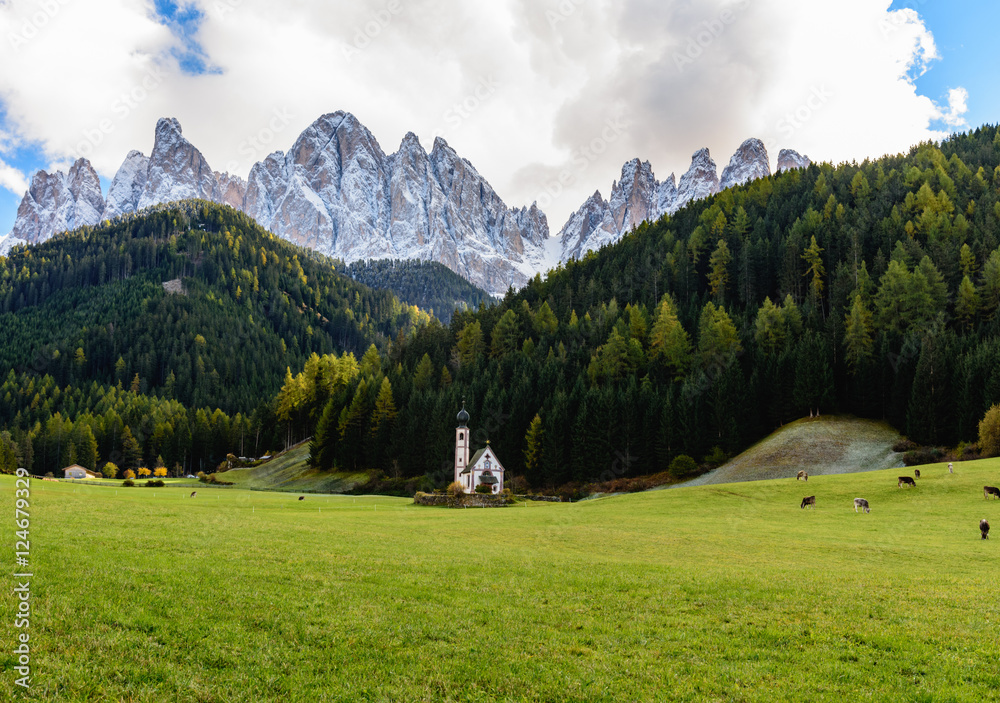 Colors of Dolomites in autumn with a church in the middle of a meadow