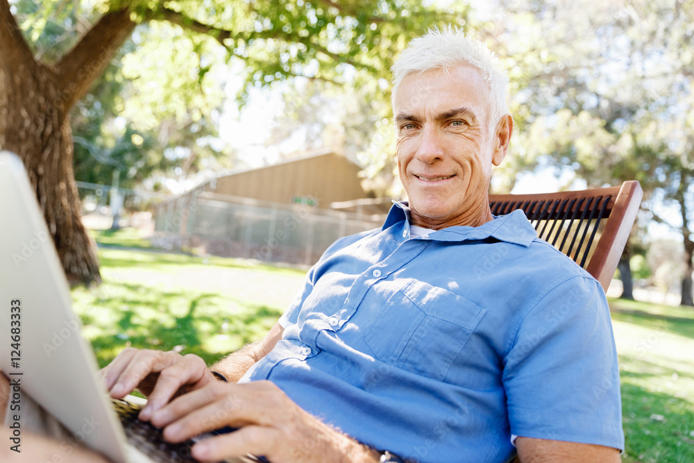 Senior man with notebook sitting in the park Senior man with notebook sitting in the park