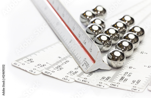 Ruler scale and ball bearings on white background