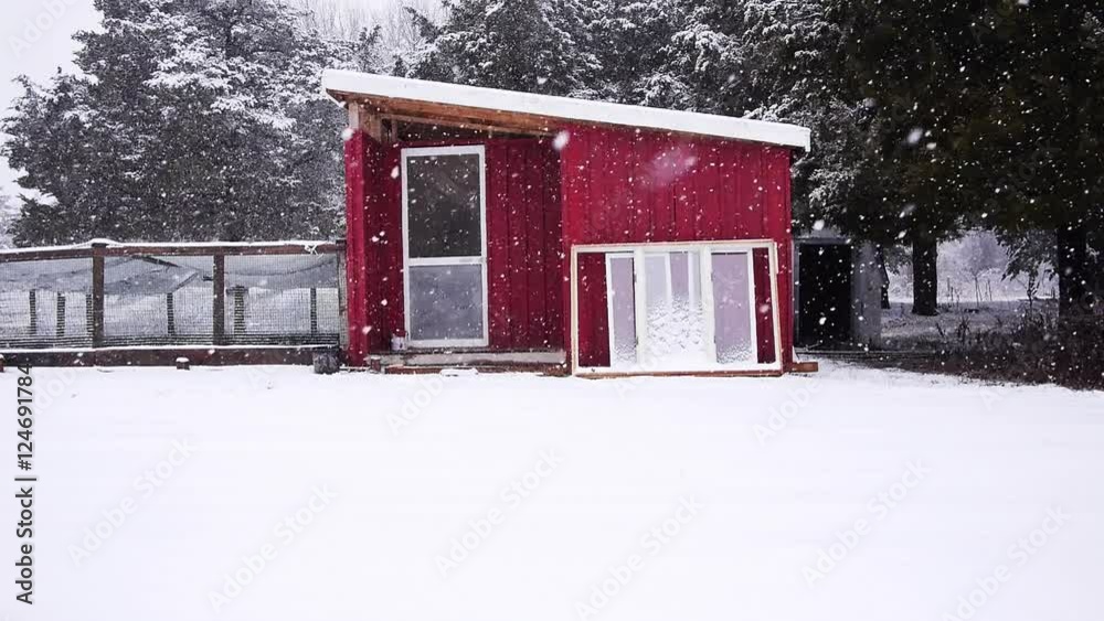 Small modern tiny home exterior during snowstorm, 