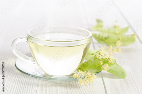 Glass cup of tea with linden on white wooden table