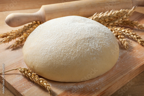 Fresh dough on a board with ears of wheat and rolling pin. photo