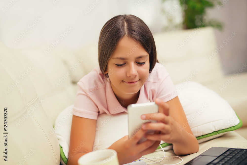 Happy girl using a mobile phone lying on the bed at home Happy girl using a mobile phone lying on the bed at home