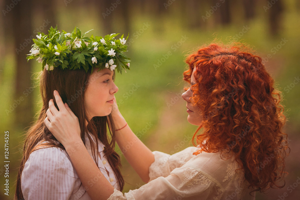 Naklejka premium incredibly beautiful woman and daughter standing in the wood