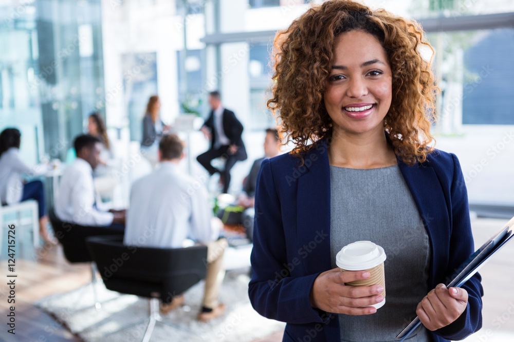 Smiling businesswoman holding coffee in office Smiling businesswoman holding coffee in office