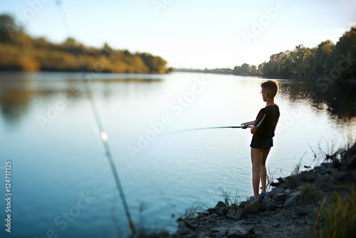 Teenage boy fishing on a fishing tackle in the river in summer