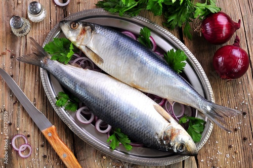 salted herring with red onion and parsley on the old wooden background. photo