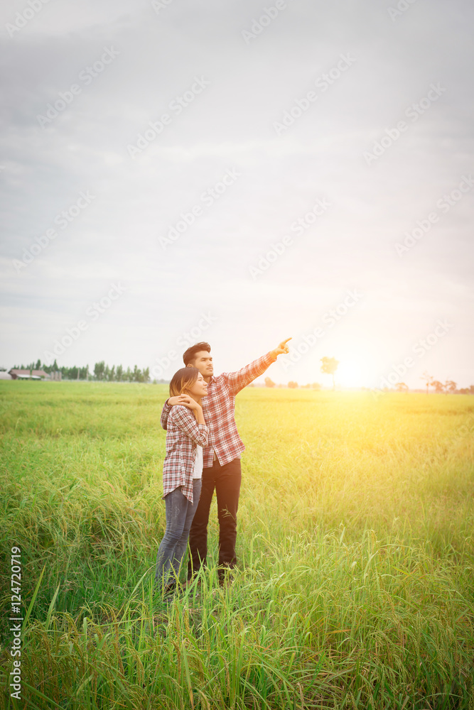 Young hipster couple standing on field pointing look away to the