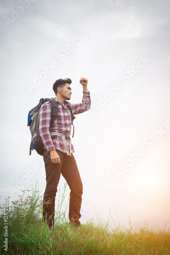 Portrait of young hipster man outdoor raising hands with backpac