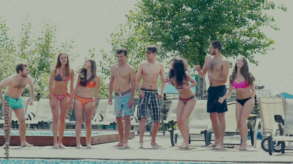 Slowmotion. Pool party. Happy fun loving group of friends running, jumping and diving into swimming pool at a pool party. In slow motion. Youth jumping in the pool.