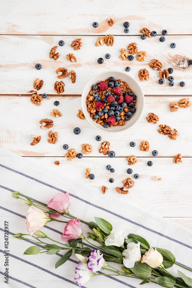 Flowers, napkin, cereals with berries and nuts on wooden background Flowers, napkin, cereals with berries and nuts on wooden background