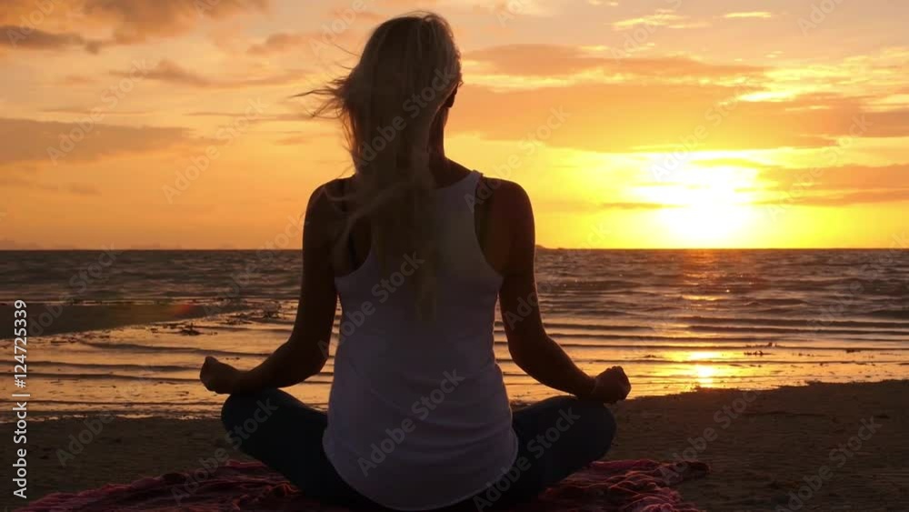 Woman Meditating at Sunset Beach in Lotus Pose Woman Meditating at Sunset Beach in Lotus Pose