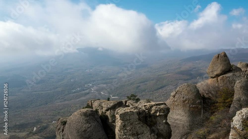 Clouds fly over a mountain valley, 
bizarre rock formations, horizontal camera movement, timelapse